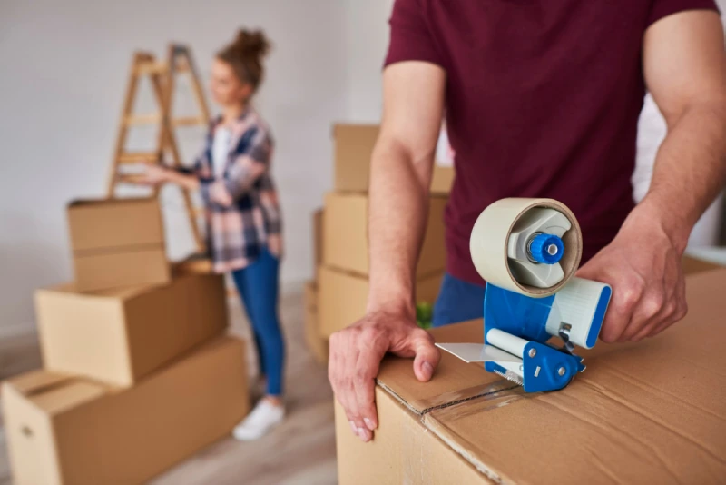 man-with-adhesive-tape-packing-boxes